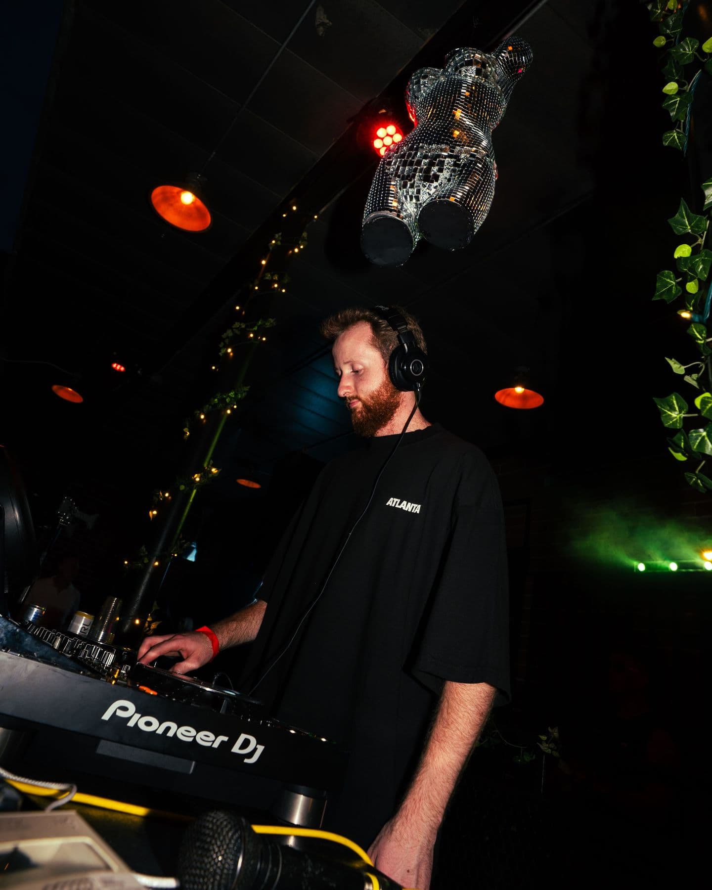 A DJ at the Pioneer decks under string lights